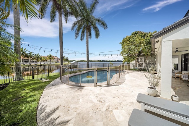 view of swimming pool with a water view, ceiling fan, a yard, and a patio