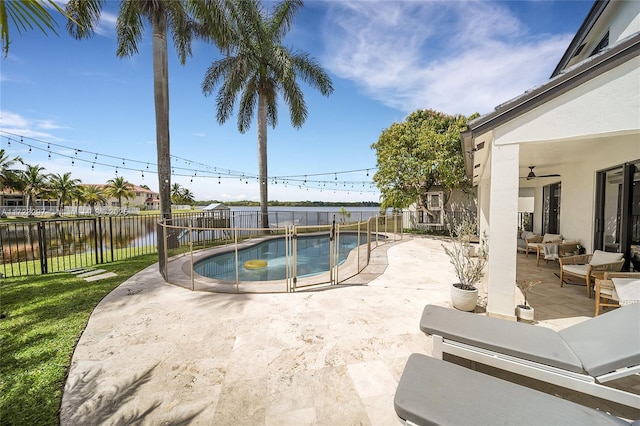 view of swimming pool featuring ceiling fan, a water view, and a patio