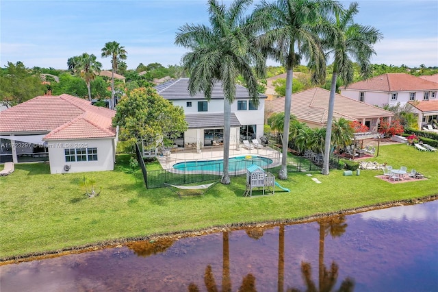 rear view of property featuring a water view, a lawn, and a patio area