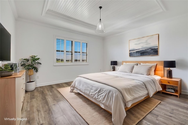 bedroom with hardwood / wood-style flooring, a raised ceiling, and ornamental molding