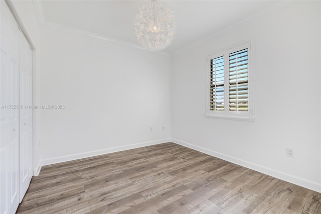 spare room with an inviting chandelier, hardwood / wood-style floors, and crown molding