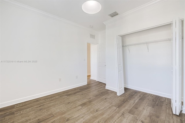 unfurnished bedroom featuring crown molding, wood-type flooring, and a closet