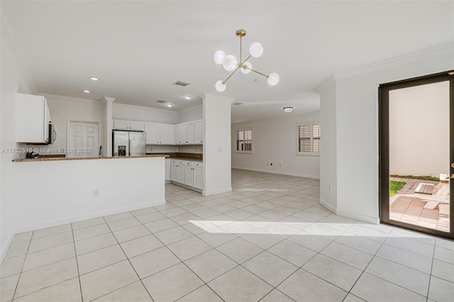 kitchen with kitchen peninsula, white cabinets, ornamental molding, a chandelier, and stainless steel appliances