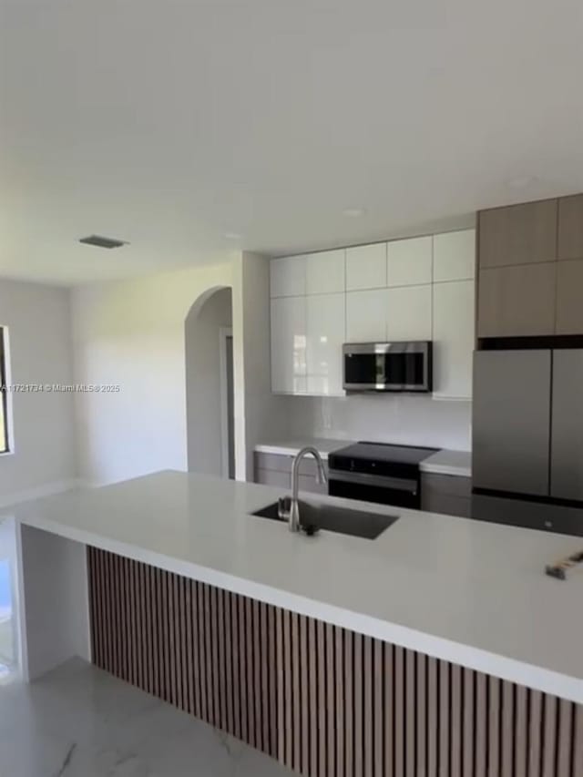 kitchen with electric range, white cabinetry, and sink