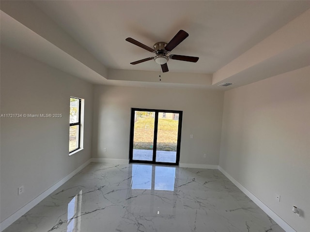 spare room featuring a raised ceiling and ceiling fan