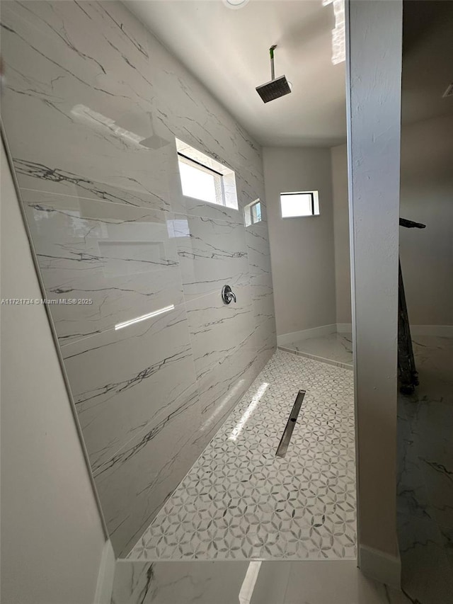 bathroom with tiled shower and baseboards