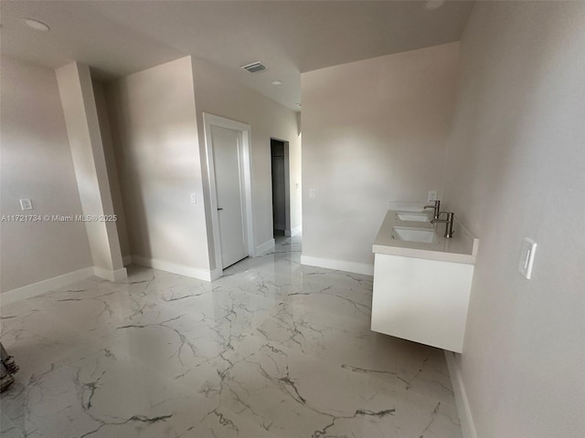 bathroom with baseboards, marble tiled floors, and double vanity