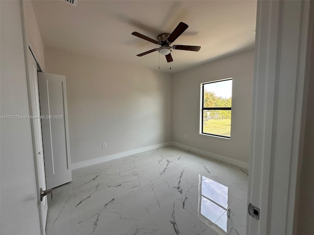 spare room with baseboards, light marble finish floors, and a ceiling fan