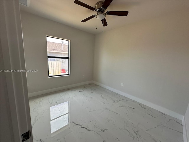empty room featuring light marble finish floors, baseboards, and ceiling fan