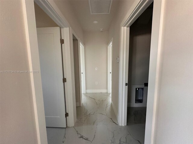 hallway with marble finish floors and baseboards