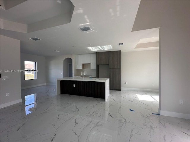 kitchen featuring modern cabinets, baseboards, arched walkways, white cabinets, and light countertops
