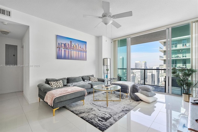 tiled living room featuring a textured ceiling, ceiling fan, electric panel, and floor to ceiling windows