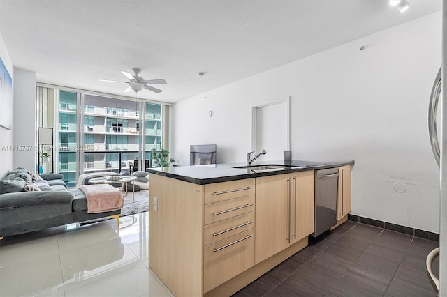 kitchen featuring ceiling fan, a wall of windows, light brown cabinets, stainless steel dishwasher, and sink