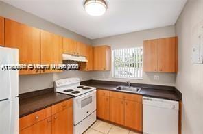 kitchen with white appliances, sink, and light tile patterned floors