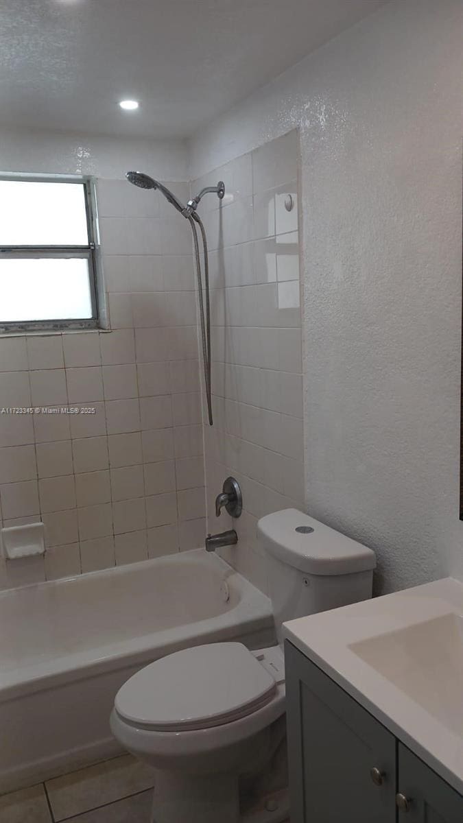 full bathroom featuring toilet, vanity, tiled shower / bath combo, and tile patterned flooring