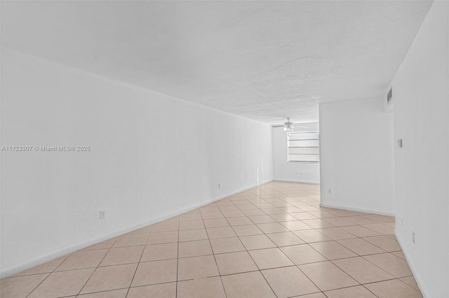 empty room with ceiling fan, light tile patterned floors, and a textured ceiling