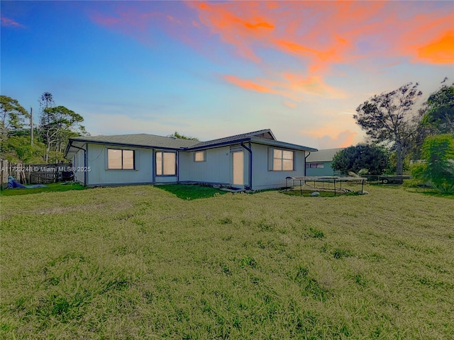 property exterior at dusk with a trampoline and a lawn