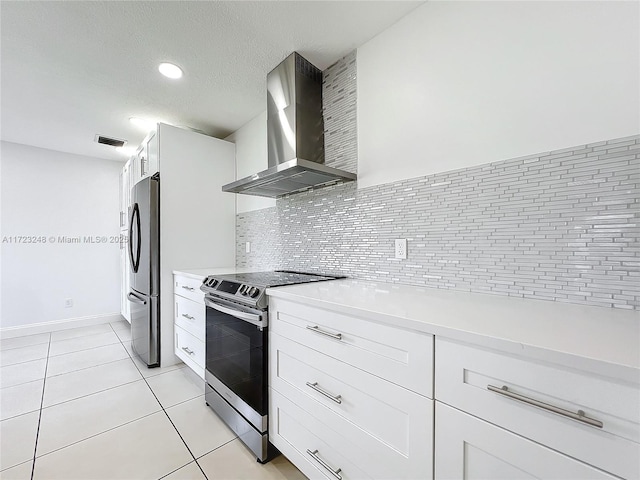 kitchen featuring light tile patterned floors, appliances with stainless steel finishes, wall chimney range hood, decorative backsplash, and white cabinets