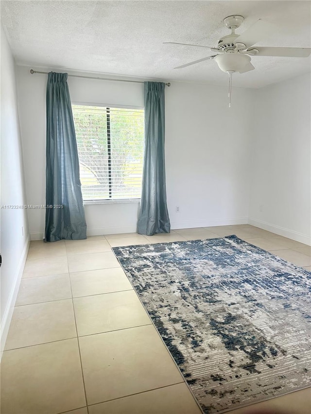 empty room featuring tile patterned flooring, ceiling fan, and a textured ceiling