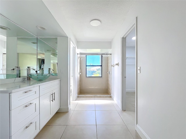 bathroom with vanity, tile patterned flooring, a textured ceiling, and a tile shower