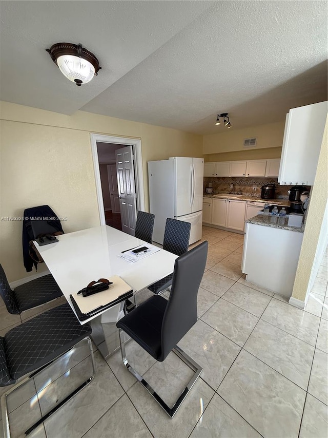 tiled dining room featuring sink and a textured ceiling