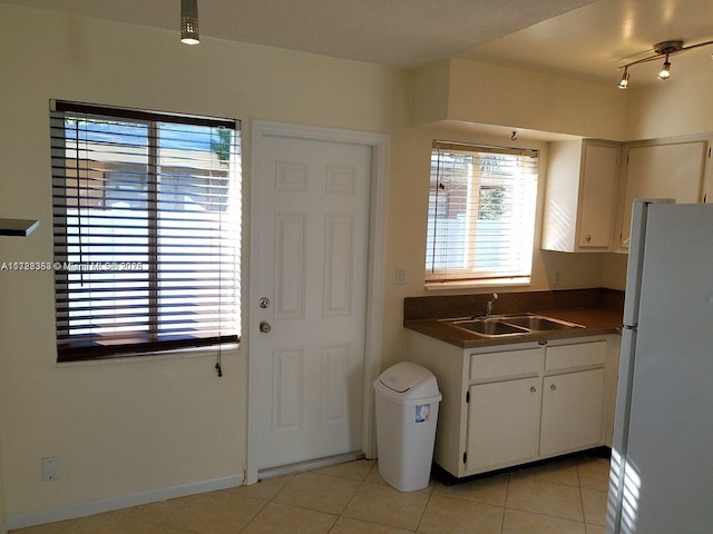 kitchen with light tile patterned flooring, white refrigerator, white cabinetry, and sink