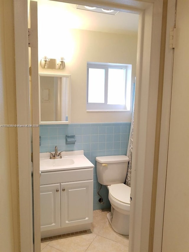 bathroom with tile patterned floors, vanity, toilet, and tile walls