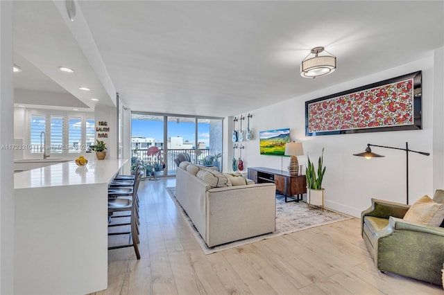 living area featuring recessed lighting, baseboards, floor to ceiling windows, and light wood finished floors