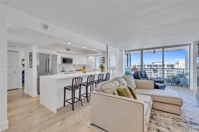 living room featuring sink, a wall of windows, and light hardwood / wood-style floors