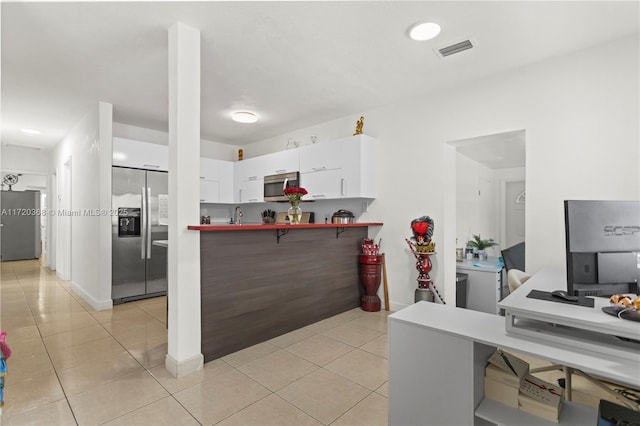 kitchen with light tile patterned floors, white cabinetry, kitchen peninsula, and appliances with stainless steel finishes