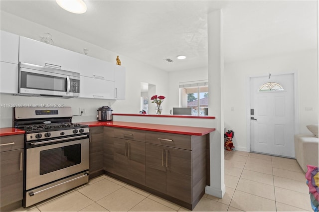 kitchen featuring white cabinets, dark brown cabinets, stainless steel appliances, and light tile patterned floors