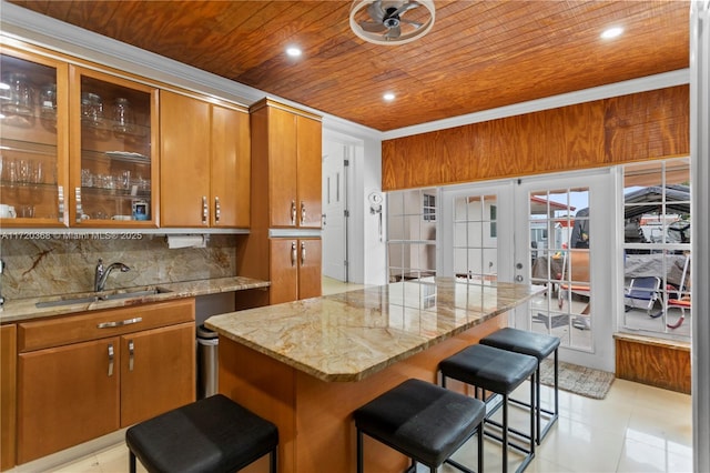 kitchen with wooden ceiling, french doors, sink, decorative backsplash, and a breakfast bar area