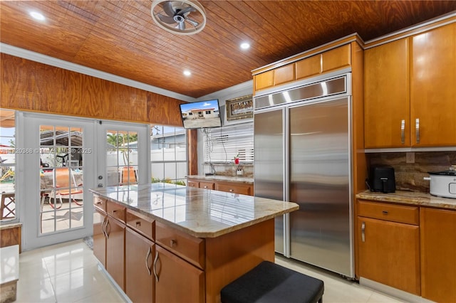 kitchen with french doors, a center island, wooden ceiling, built in fridge, and light tile patterned floors