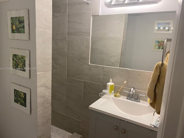 bathroom with vanity, decorative backsplash, and tiled shower