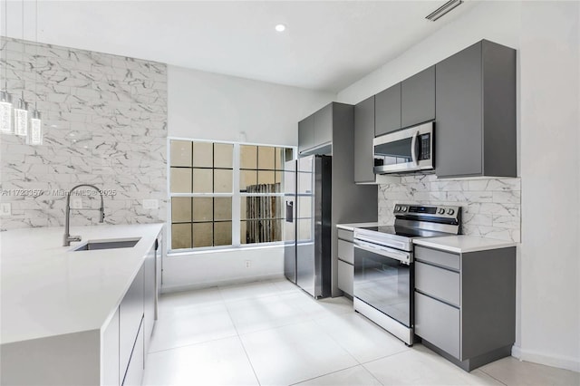 kitchen featuring light tile patterned floors, stainless steel appliances, gray cabinetry, and sink