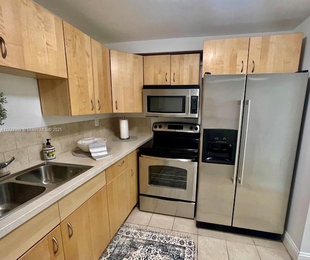 kitchen featuring appliances with stainless steel finishes, light tile patterned floors, and light brown cabinetry