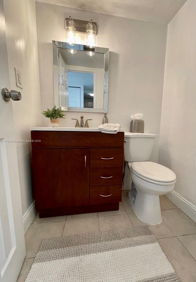 bathroom with toilet, vanity, and tile patterned floors