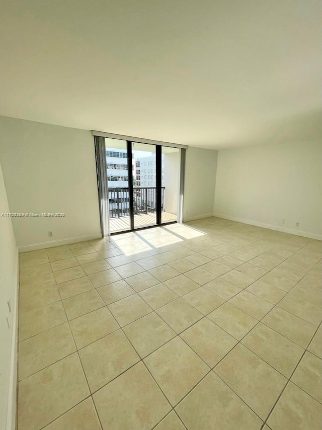 empty room featuring expansive windows and light tile patterned flooring