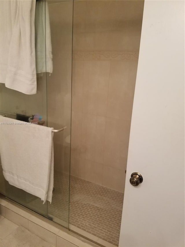 bathroom with a tile shower and tile patterned floors