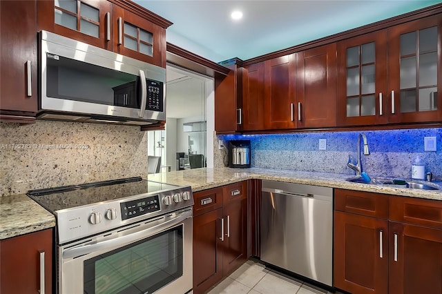 kitchen featuring tasteful backsplash, light stone counters, sink, and stainless steel appliances