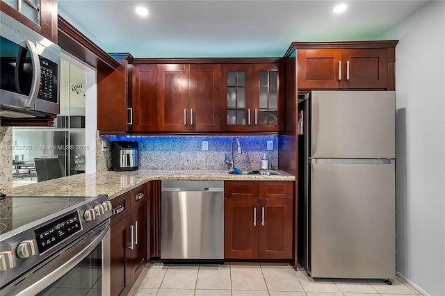 kitchen featuring light stone countertops, appliances with stainless steel finishes, tasteful backsplash, sink, and light tile patterned flooring