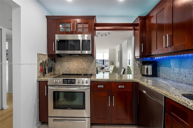 kitchen with decorative backsplash, appliances with stainless steel finishes, and light stone countertops