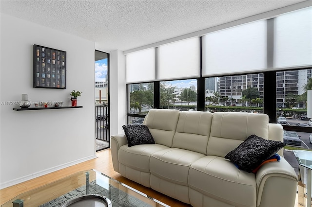 living room featuring a textured ceiling, light wood-type flooring, and a wall of windows