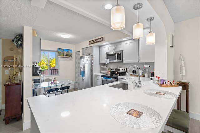 kitchen featuring kitchen peninsula, decorative light fixtures, stainless steel appliances, and sink