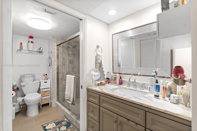 bathroom featuring a shower with door, vanity, and toilet