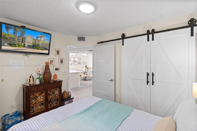 bedroom featuring a barn door and a textured ceiling