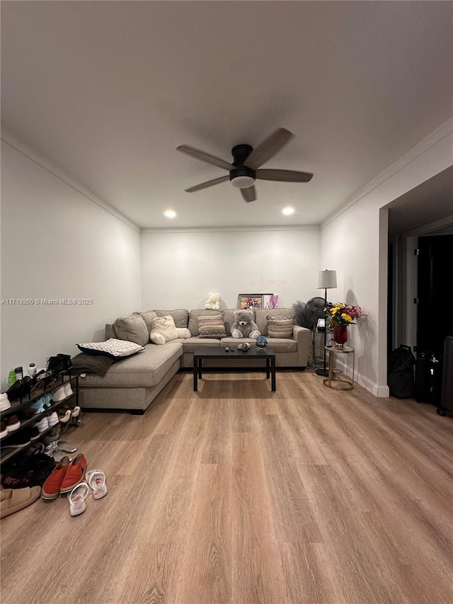 living room with crown molding, light hardwood / wood-style flooring, and ceiling fan