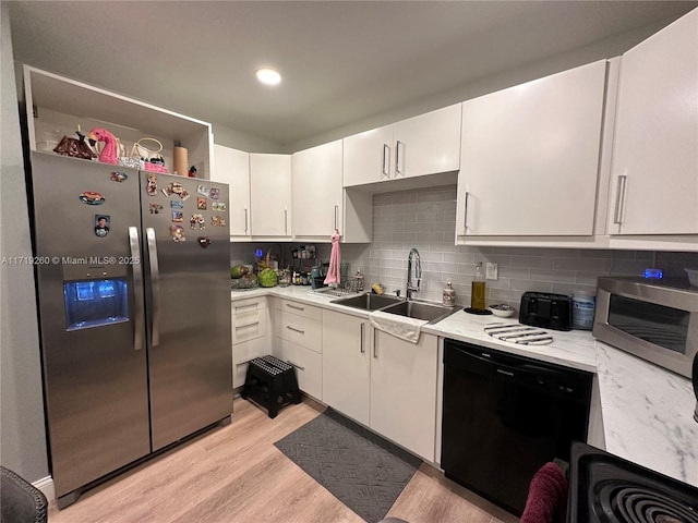 kitchen with sink, light hardwood / wood-style flooring, decorative backsplash, appliances with stainless steel finishes, and white cabinetry