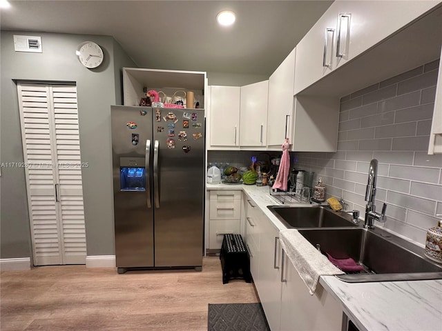 kitchen featuring sink, stainless steel fridge with ice dispenser, light hardwood / wood-style floors, decorative backsplash, and white cabinets