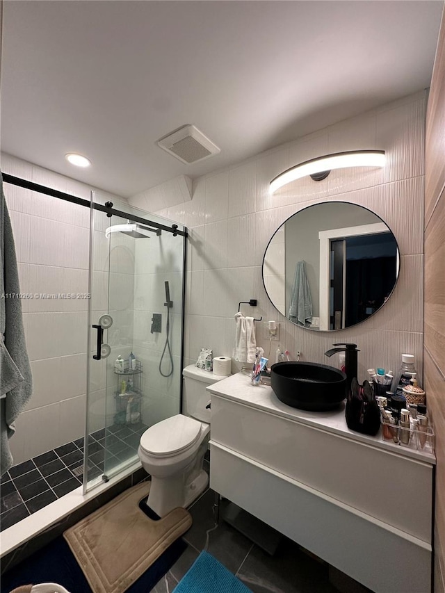 bathroom featuring tile patterned floors, a shower with door, vanity, and tile walls